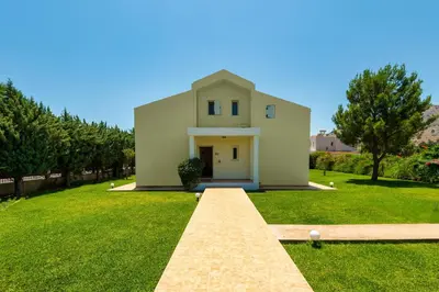 a small white house with a grass yard at Apollo Villa in Kolimbia