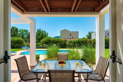 a patio with a table and chairs and a pool at Apollo Villa in Kolimbia