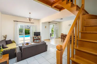 a living room with a couch and a staircase at Apollo Villa in Kolimbia
