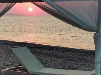 a lounge chair on the beach with the sunset at Villa Akti in Lachania