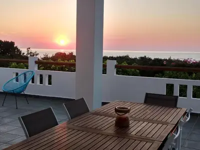 a wooden table and chairs on a balcony with the sunset at Villa Akti in Lachania