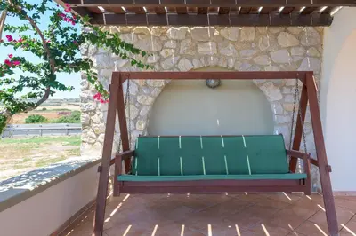 a green bench sitting under a stone wall at Villa Lahania in Lachania