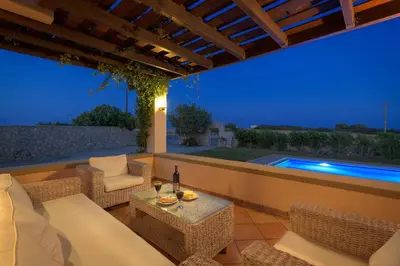 a patio with a table and chairs and a swimming pool at Villa Lahania in Lachania
