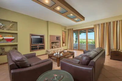 a living room with two leather couches and a television at Villa Lahania in Lachania