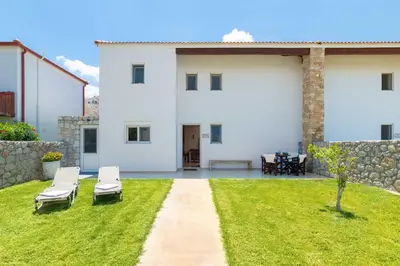 a white house with two chairs in the yard at Kolymbia Villas by StayonRhodes in Kolimbia