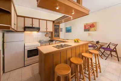 a kitchen with wooden cabinets and a island with bar stools at Apartment Dream Holidays - 500 meters to beach in Ialyssos