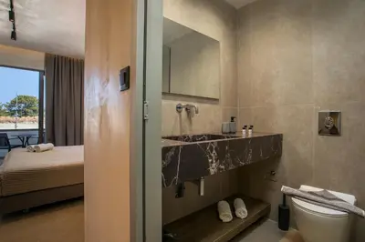 a bathroom with a sink and a toilet and a bed at Ano Kampos Hotel in Faliraki