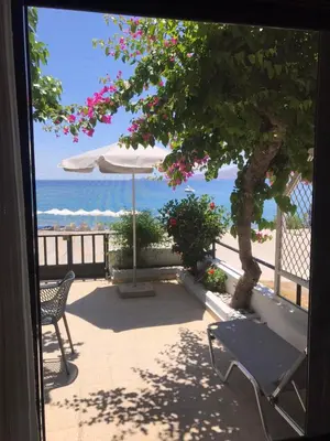 a patio with a tree and an umbrella and a chair at Haraki Beach House in Haraki