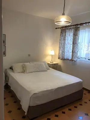 a bedroom with a bed and a lamp and a window at Haraki Beach House in Haraki