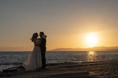 a bride and groom kissing on the beach at sunset at Axiotheaton Villas in Pefki Rhodes