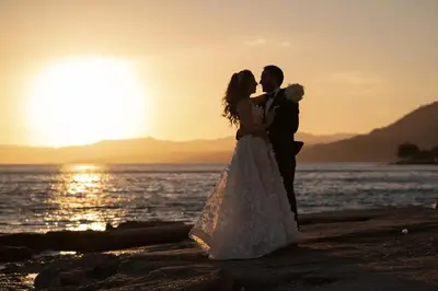 a bride and groom standing on the beach at sunset at Axiotheaton Villas in Pefki Rhodes