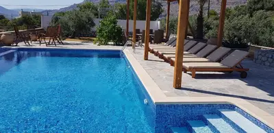 a swimming pool with chaise lounges and a table and chairs at Villa Sealine in Pefki Rhodes