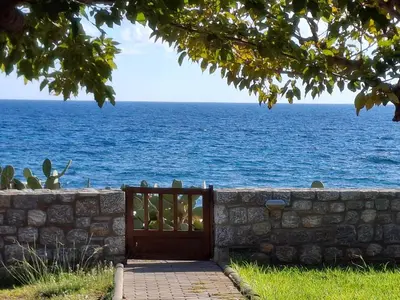 a gate to a stone wall and the ocean at Alisahni Beachfront Villas in Kiotari