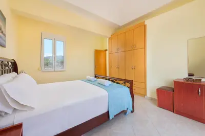 a bedroom with a large white bed and a tv at Orianna Sea View Villa in Gennadi