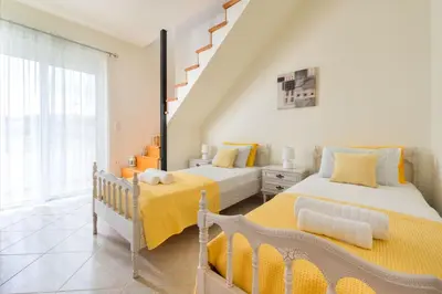 a bedroom with two beds and a staircase at Orianna Sea View Villa in Gennadi