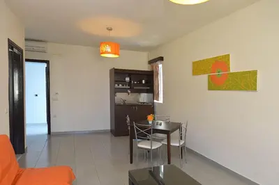 a living room with a table and a kitchen at Ialysos City Hotel in Ialyssos