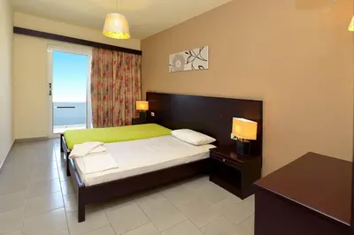 a bedroom with a bed with a green headboard and a window at Ialysos City Hotel in Ialyssos