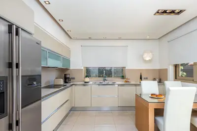 a kitchen with white cabinets and a stainless steel refrigerator at Vasiliki Villa in Ialyssos