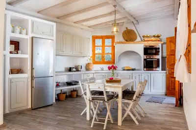 a kitchen with white cabinets and a table and chairs at Lindos Seaside Villa in Líndos