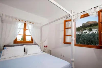 a white bedroom with a bed and a window at Lindos Seaside Villa in Líndos