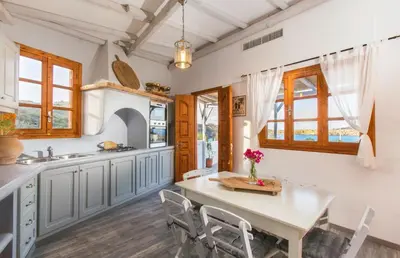a kitchen with a table and chairs and windows at Lindos Seaside Villa in Líndos