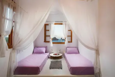 two beds in a room with curtains and a window at Lindos Seaside Villa in Líndos