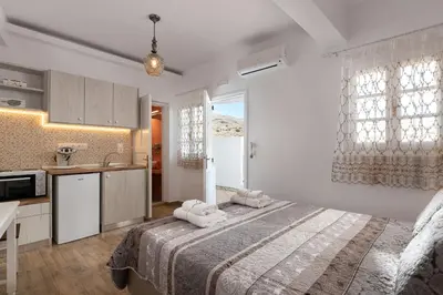 a bedroom with a large bed and a kitchen at Chrysanthi Studios in Líndos