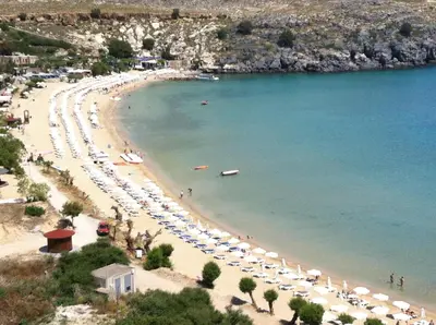 a beach with a bunch of umbrellas and people at Chrysanthi Studios in Líndos