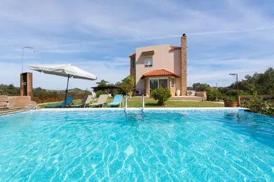a villa with a swimming pool in front of a house at Natura House in Ialyssos