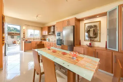 a kitchen with wooden cabinets and a large counter top at Natura House in Ialyssos