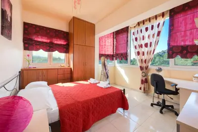 a bedroom with a red bed and a desk and windows at Natura House in Ialyssos