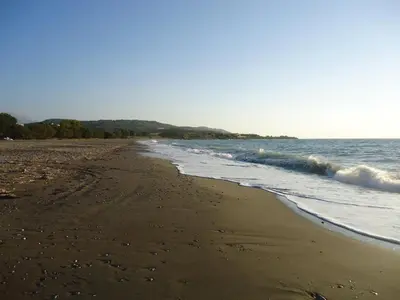 a sandy beach with waves coming in from the ocean at Alexandra Homestay in Kalavárda