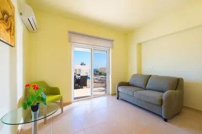 a living room with a couch and a glass table at Athoniki Villas in Kalathos