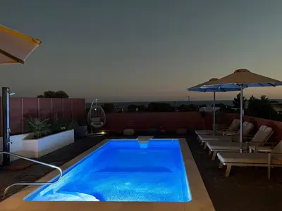 a swimming pool with an umbrella and some chairs and an umbrella at Milos Villas Complex in Pefki Rhodes