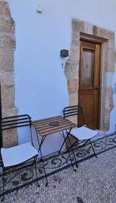 a picnic table and two chairs in front of a door at Villa Aphrodite Lindos Suites in Líndos