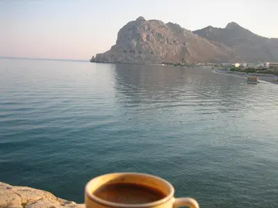 a cup of coffee sitting on a ledge near the water at Ktima Ellopia in Kolimbia