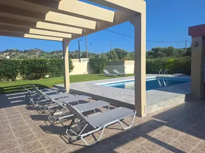 a group of lounge chairs sitting next to a swimming pool at villa de calme in Pastida
