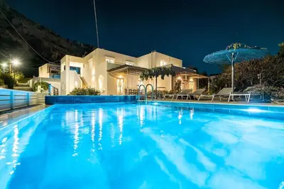 a large swimming pool in front of a house at night at Plakia Beach Apartments in Pefki Rhodes