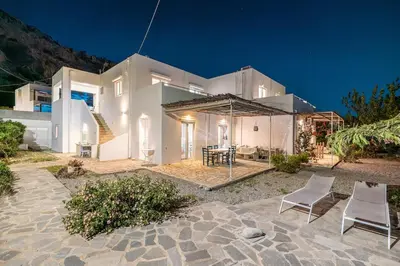 a large white house with two chairs in front of it at Plakia Beach Apartments in Pefki Rhodes