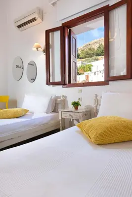 two beds in a room with a window at Lindos Citrin Studios in Líndos