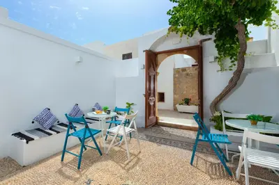 a patio with a table and chairs and a tree at Lindos Citrin Studios in Líndos