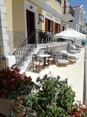 a patio with tables and chairs and an umbrella at Perla di Mare in Symi