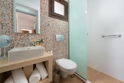 a bathroom with a sink and a toilet and a mirror at Lindos Diamond Exclusive Villa in Líndos
