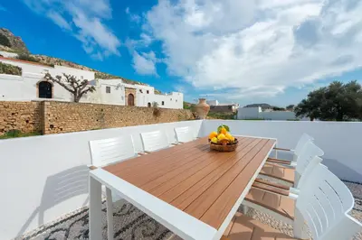 a wooden table with white chairs and a bowl of fruit at Lindos Diamond Exclusive Villa in Líndos