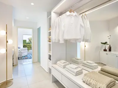a dressing room with white clothes hanging on a wall at Grecotel LUXME Dama Dama in Faliraki