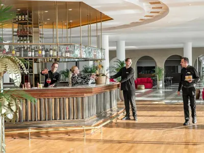 a group of men standing at a bar in a lobby at Grecotel LUXME Dama Dama in Faliraki