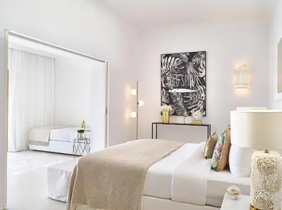 a white bedroom with a bed and a lamp at Grecotel LUXME Dama Dama in Faliraki