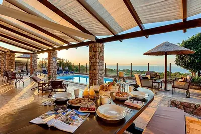 a table with food on it on a patio with a pool at Butterfly Villa with stunning Sea and Valley Views in Theologos