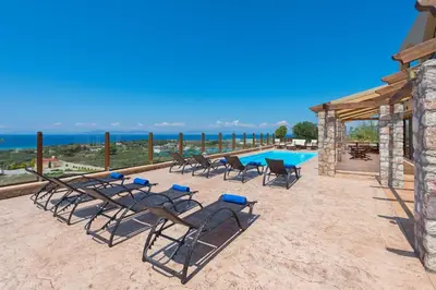 a group of chairs and a table and a pool at Butterfly Villa with stunning Sea and Valley Views in Theologos