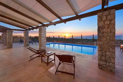 a patio with a table and chairs and a pool at Butterfly Villa with stunning Sea and Valley Views in Theologos